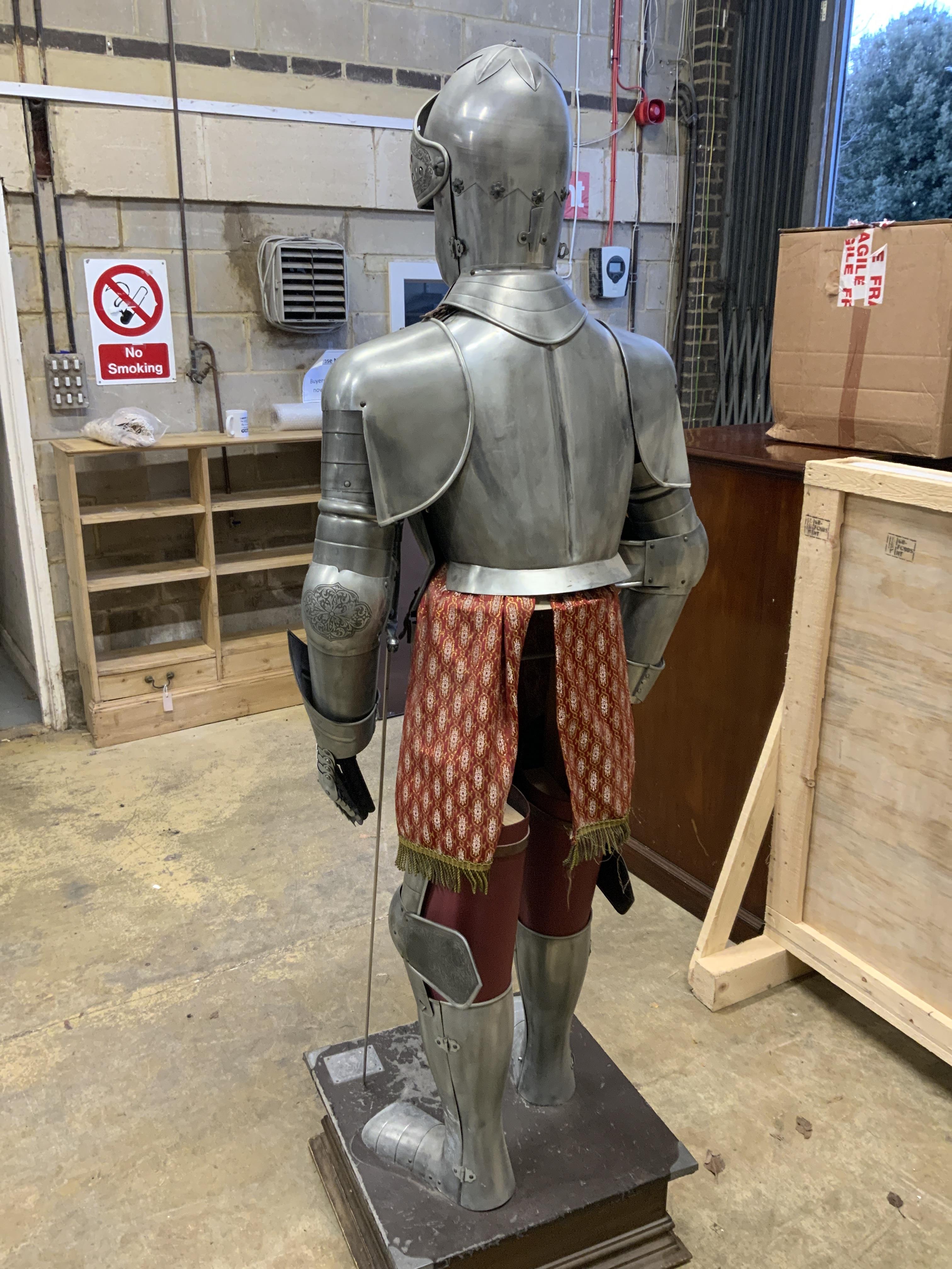 A full suit of reproduction armour produced in Spain by Marto, etch engraved decoration and including a broadsword, mounted on a display plinth and stand with applied makers label